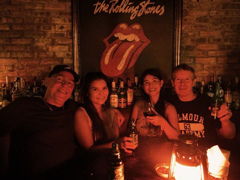 Four guests raising drinks in front of the brick bar wall