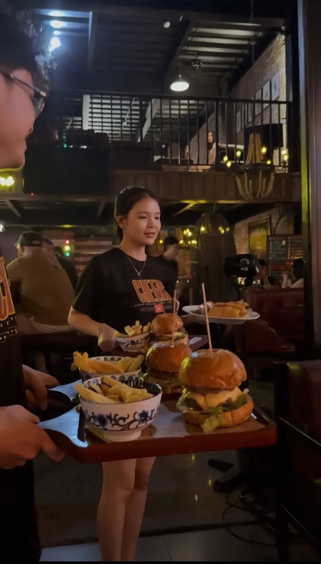 A server carrying freshly prepared burgers at Cheers